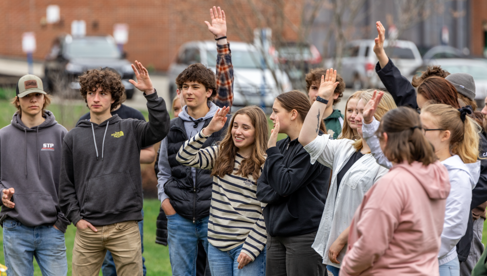 A group of high school students raises their hands