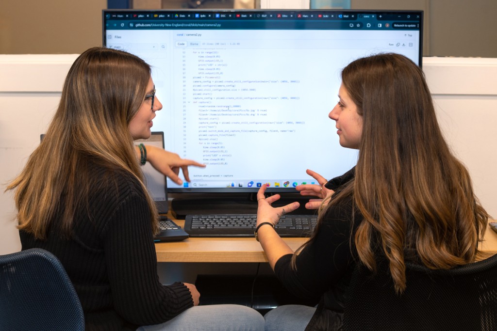 Two computer science students review computer code on a monitor