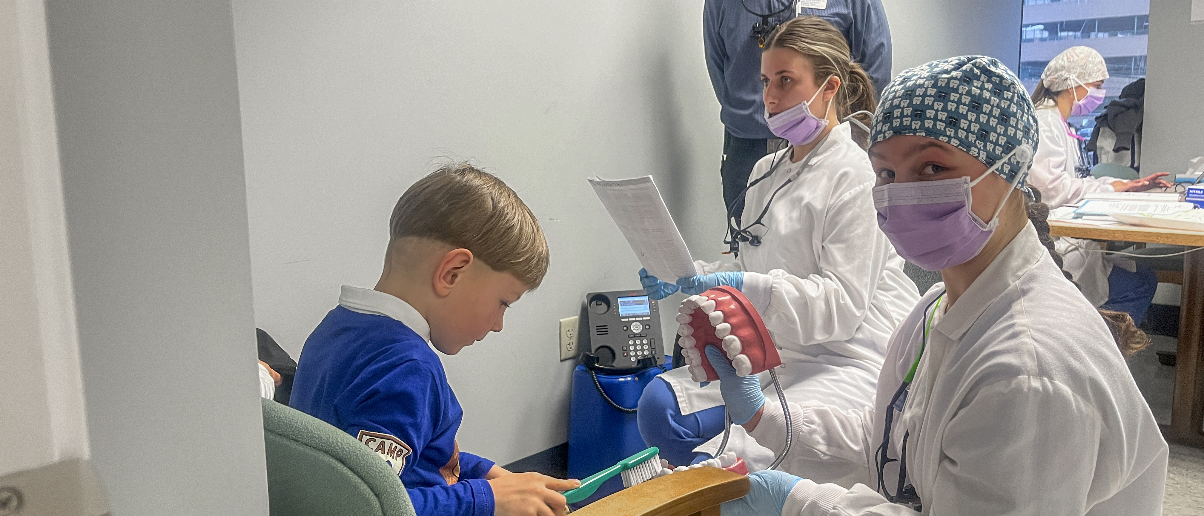 Two UNE dental hygiene students provide dental education to a child at a local social services center