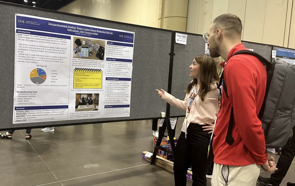 A UNE OT student explains her research poster to a conference attendee