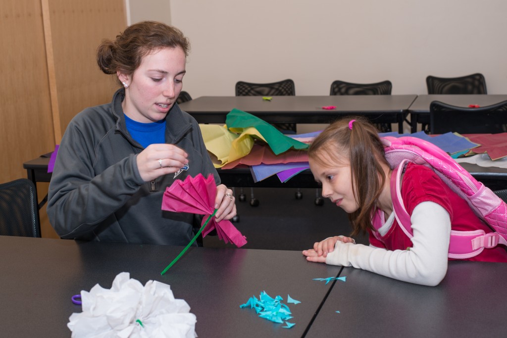 Gwenyth Breslen makes paper flowers with a student from the Boys and Girls Club