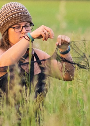 A U N E student adjusts some netting in a field