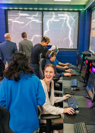 Two students smile and chat while playing video games in the Nor’easter ESport Room