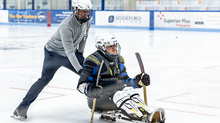 A UNE student pushes a man on a hockey sled as part of a demonstration