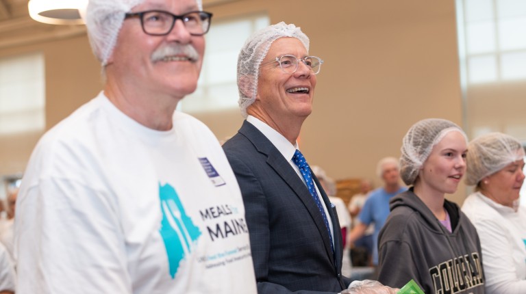 UNE President James Herbert smiles while helping pack meals at the Meals for Maine event