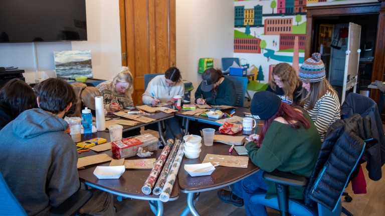 Students decorate paper bags inside the Heart of Biddeford office