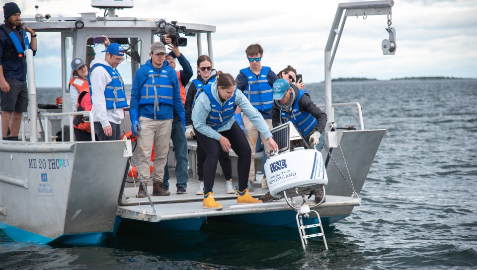 Students and researchers drop the real-time shark buoy into the ocean 