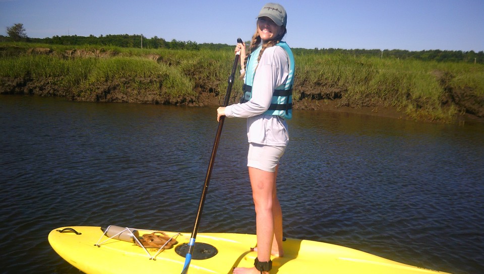 A female student navigates on a stand-up paddleboard