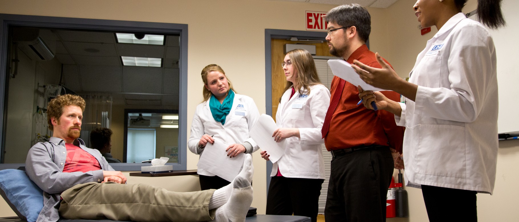 UNE students work with a standardized patient in the simulation lab