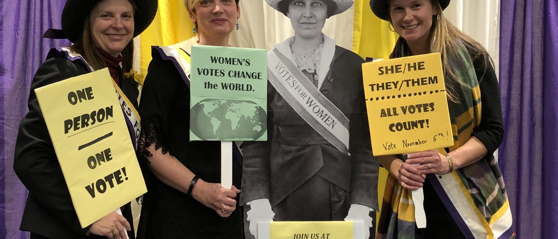 Attendees pose with an image of Katharine Dexter McCormick of the National Woman’s Suffrage Association 
