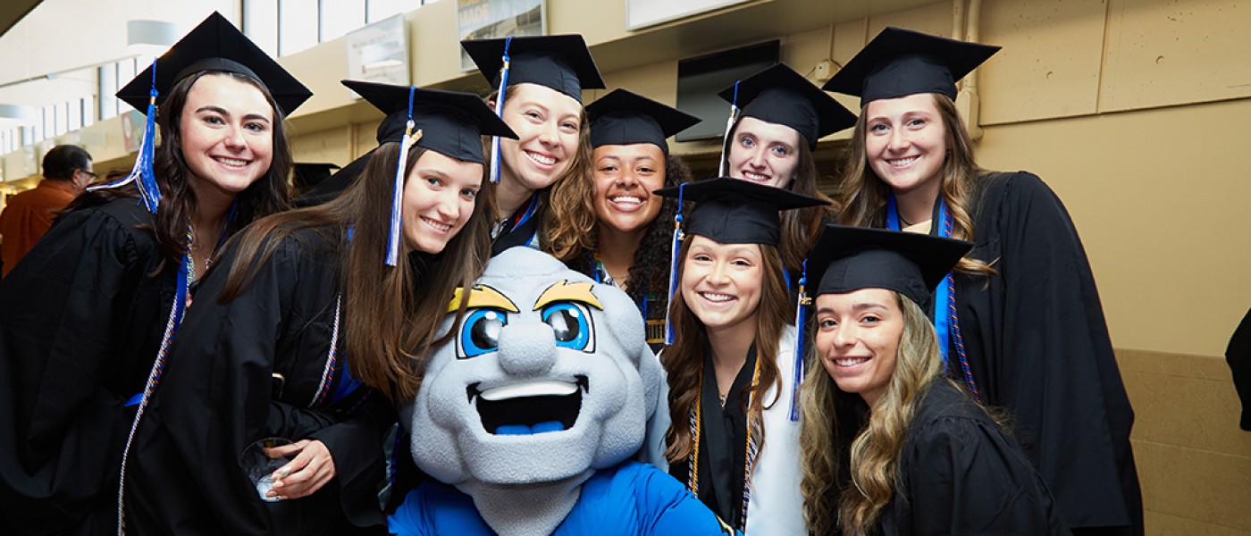 Graduates pose with UNE's mascot, Stormin' Norman