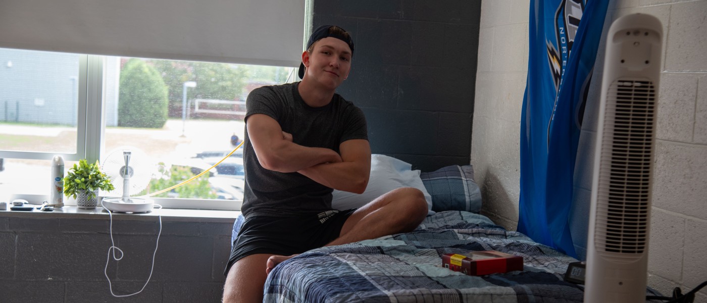 A student poses for a photo in his dorm room