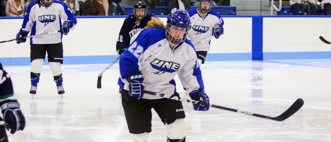 Members of the U N E women's hockey team skate toward the puck 