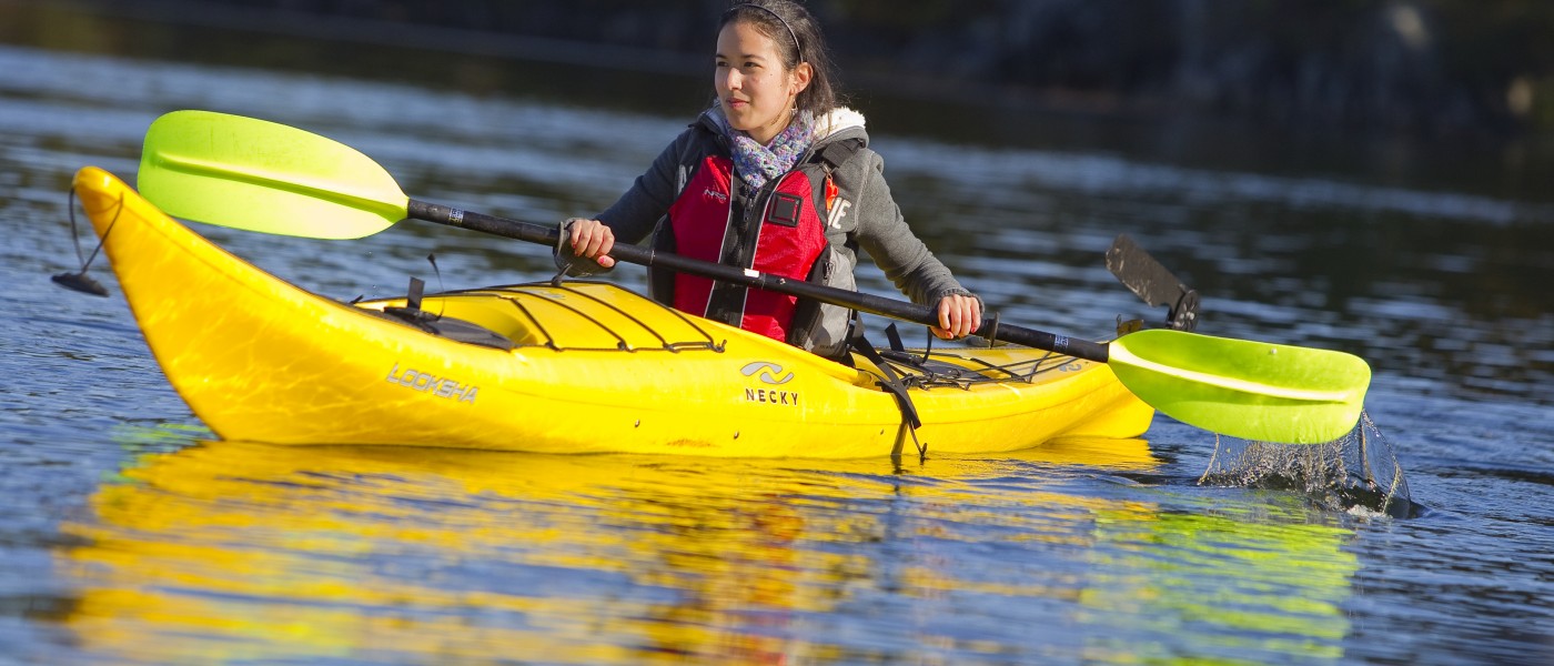 A U N E student paddles in a yellow kayak 