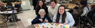 Three female students pose with a resident of Portland's Barron Center, a long-term care facility
