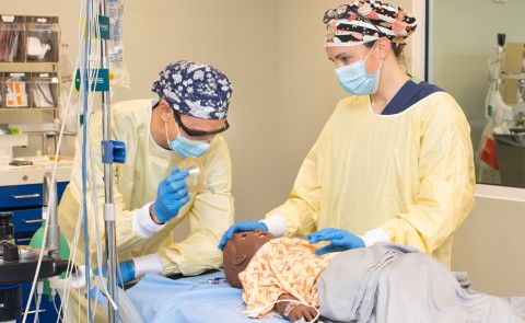 Two U N E D N P students practice on a patient simulator
