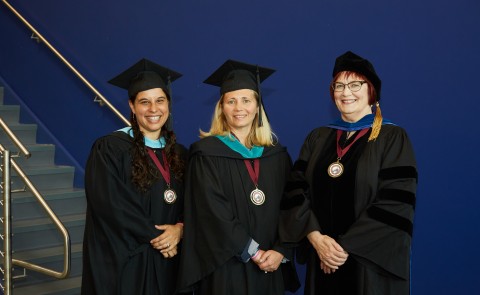 Julia Sleeper-Whiting, Hannah Pingree, and Lise Pelletier pose for a photo in academic regalia 