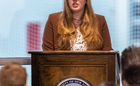 A student speaks at a podium during the PSI CHI induction ceremony