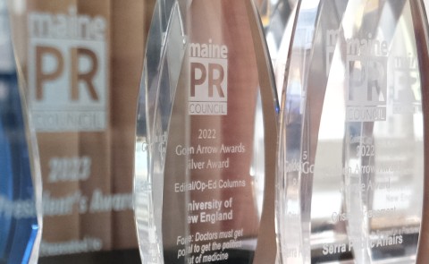 Image of a Golden Arrow award with UNE's winning op-Ed listed