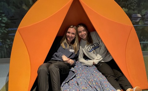 Two female students pose in an orange tent