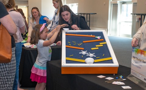 A child plays with an adaptive toy at a display table