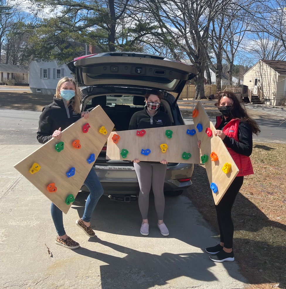 Students hold pieces of a climbing wall they made for a project