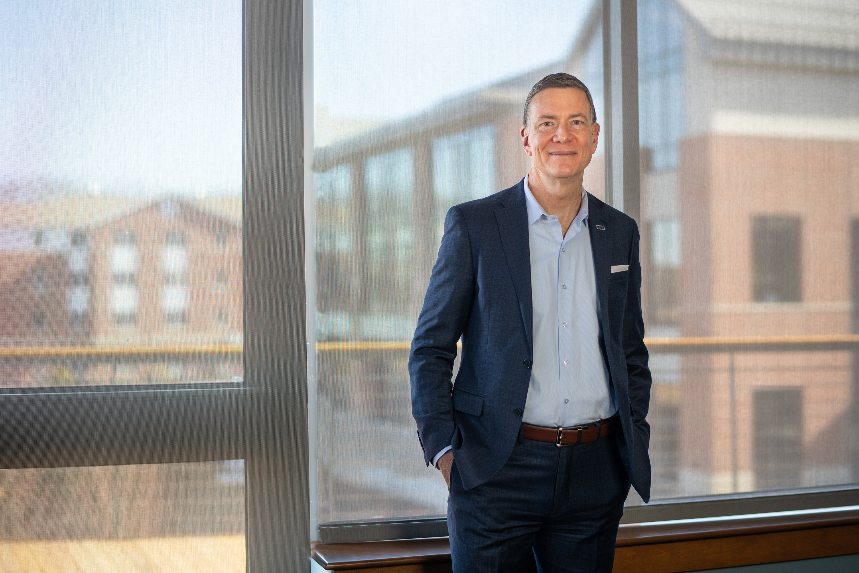 U N E President James Herbert poses in front of a window overlooking the Biddeford Campus