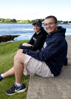 Two U N E students sitting by the water