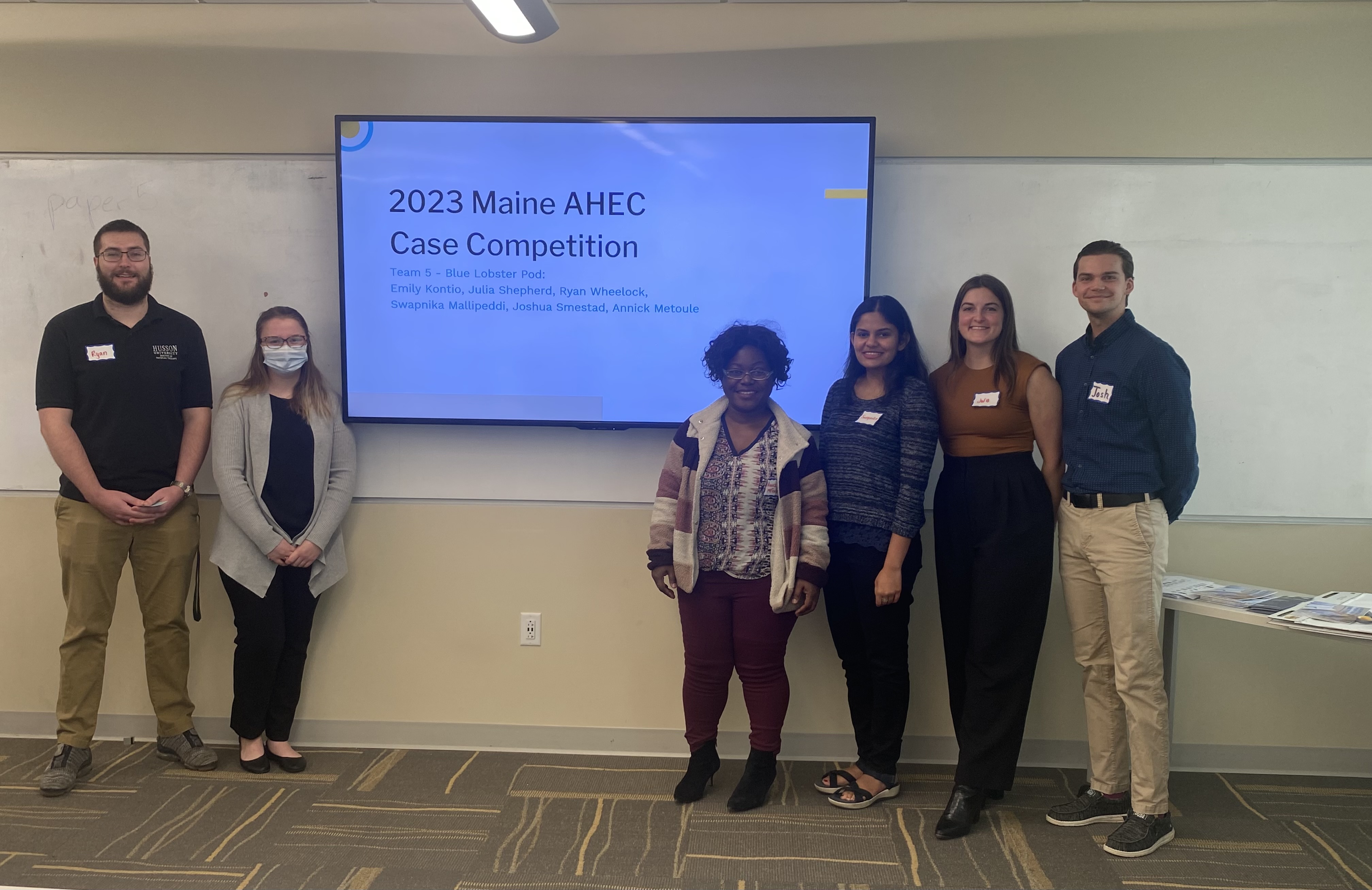 Six students pose against a projector screen in Innovation Hall