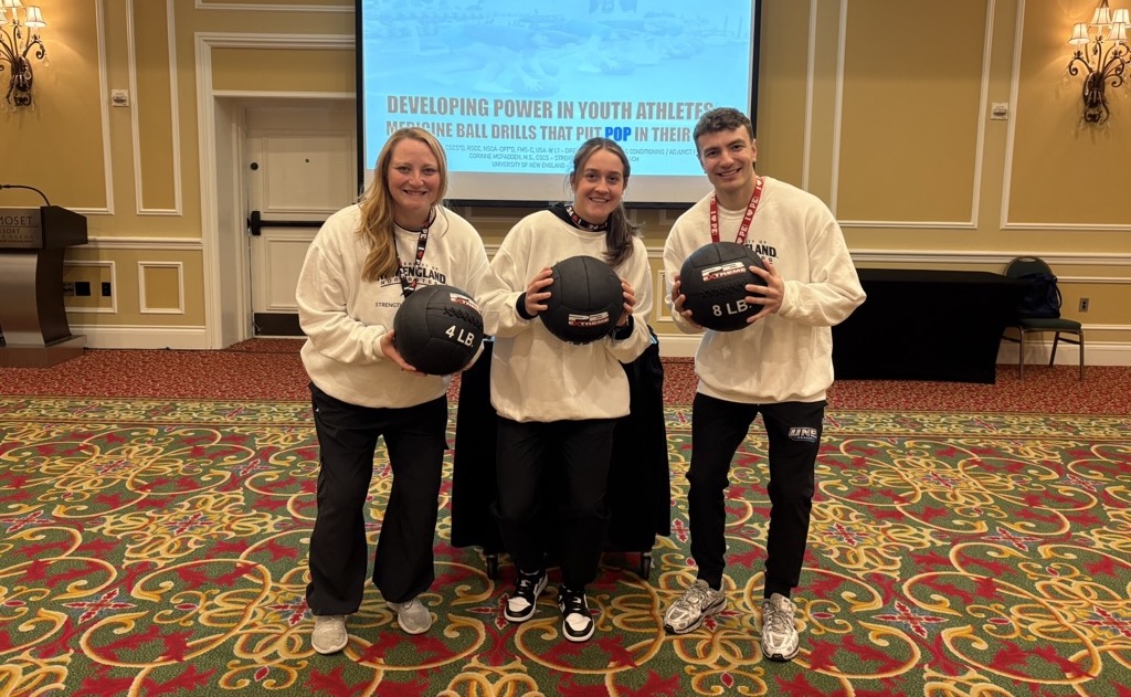 UNE student Aidan Curran poses with his research collaborators, all three are holding medicine balls
