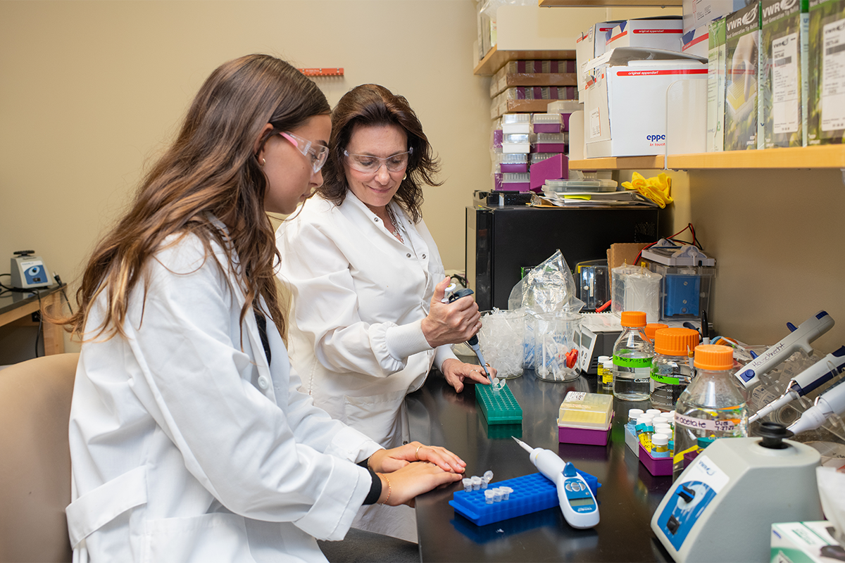 Barlow and a student researcher work together at a lab bench, preparing samples with pipettes and sample storage boxes.