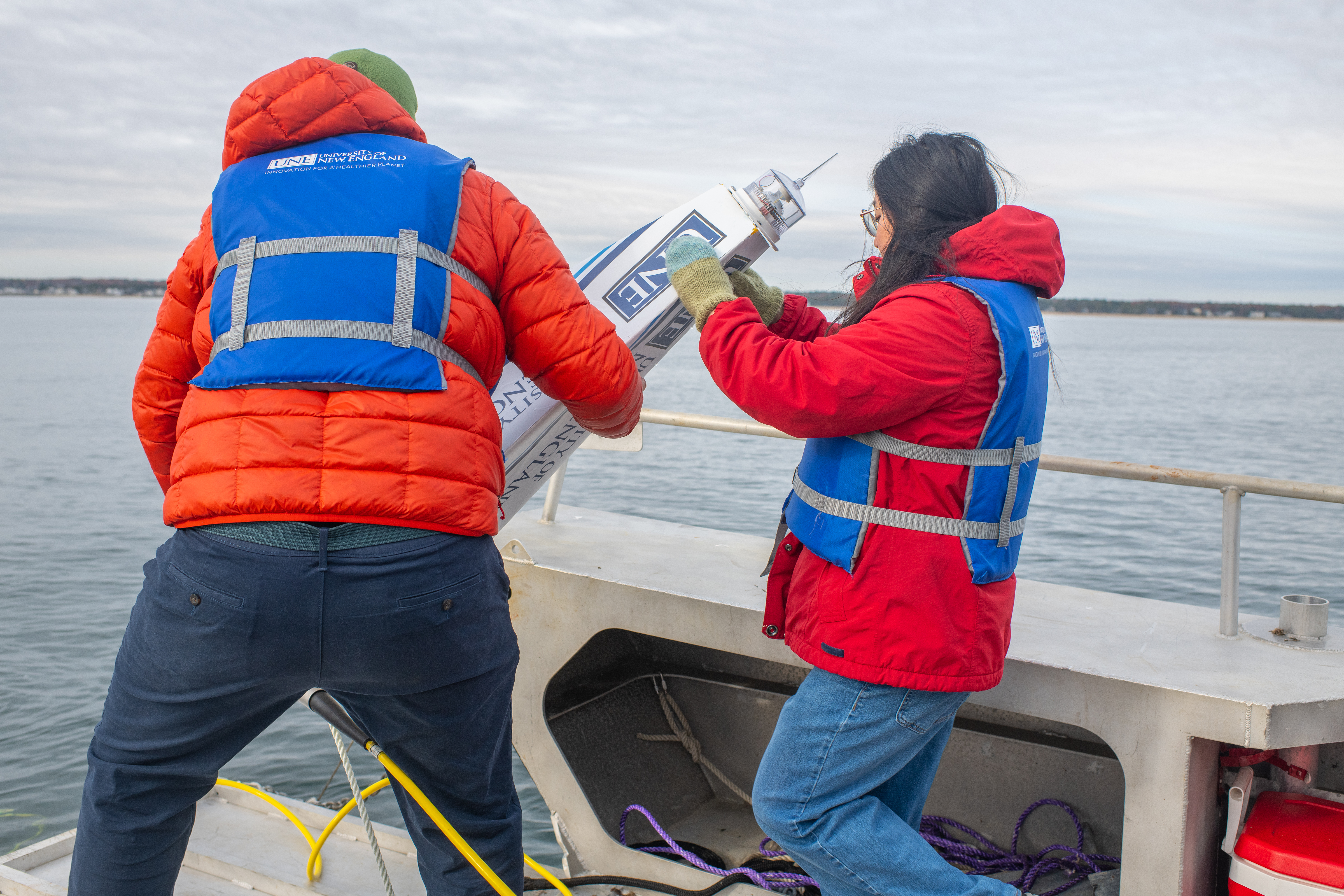 UNE student Jasmin Townsend-Ng (’26) assists Dr. Kochtitzky in lower a buoy