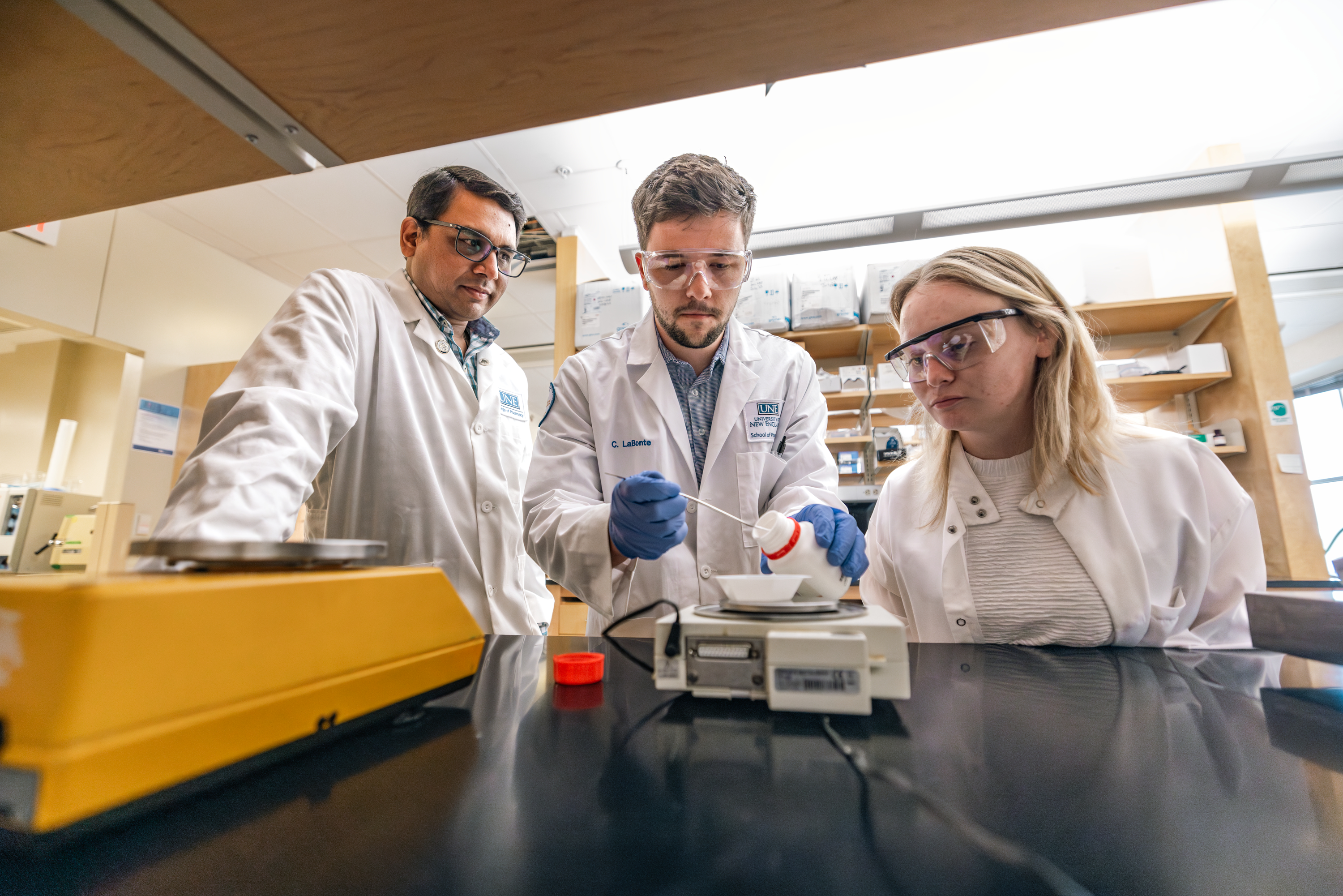 A UNE researcher and students work in a Portland Campus lab