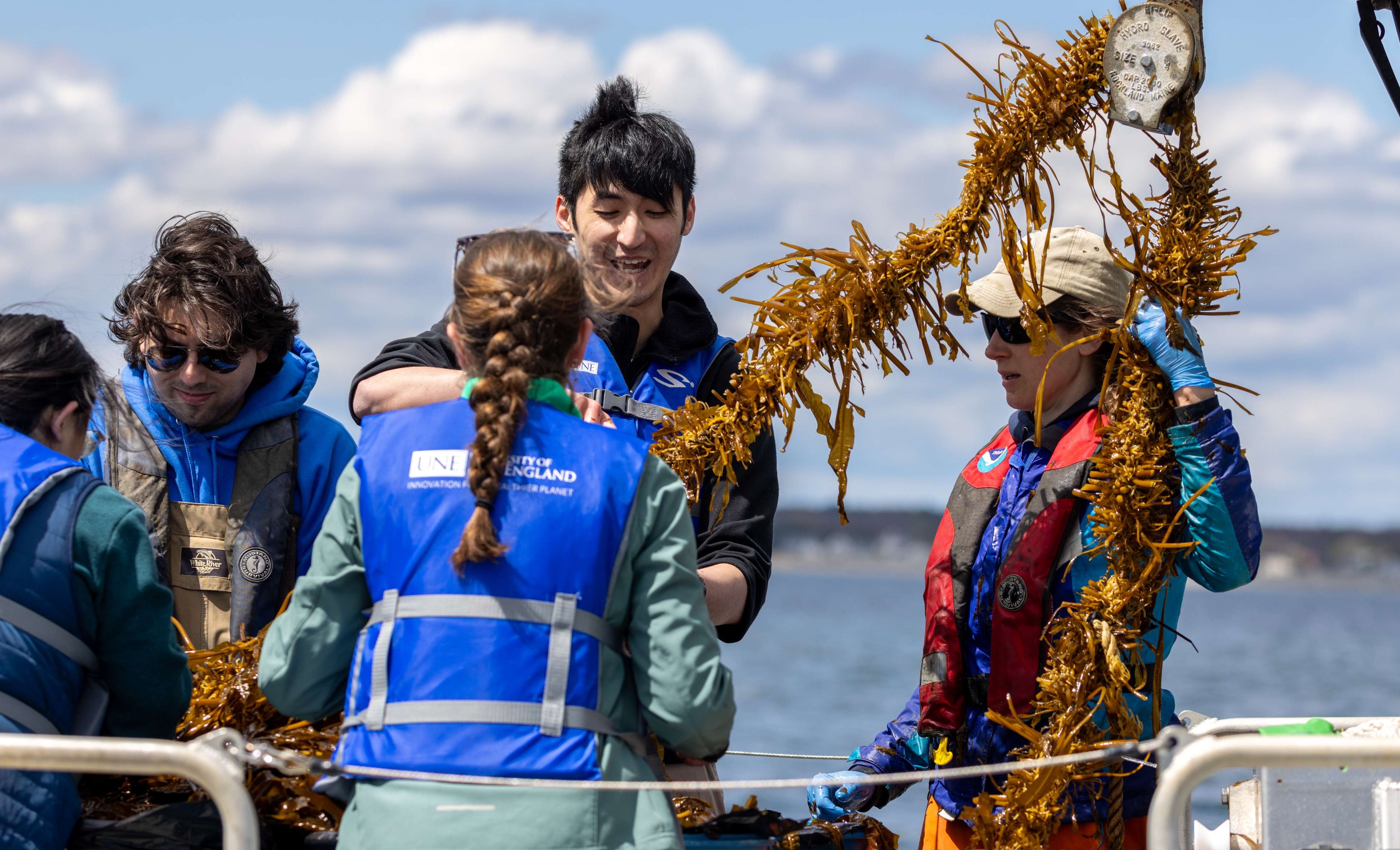 Students hoist help onto a UNE research vessel