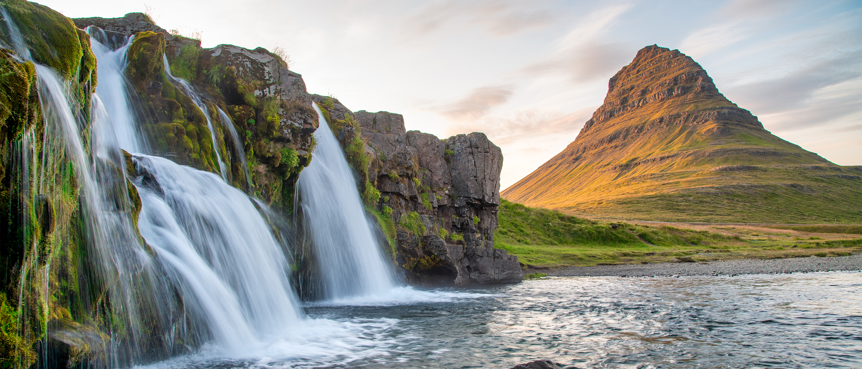 Waterfalls cascade beside Kirkjufell mountain in Iceland.