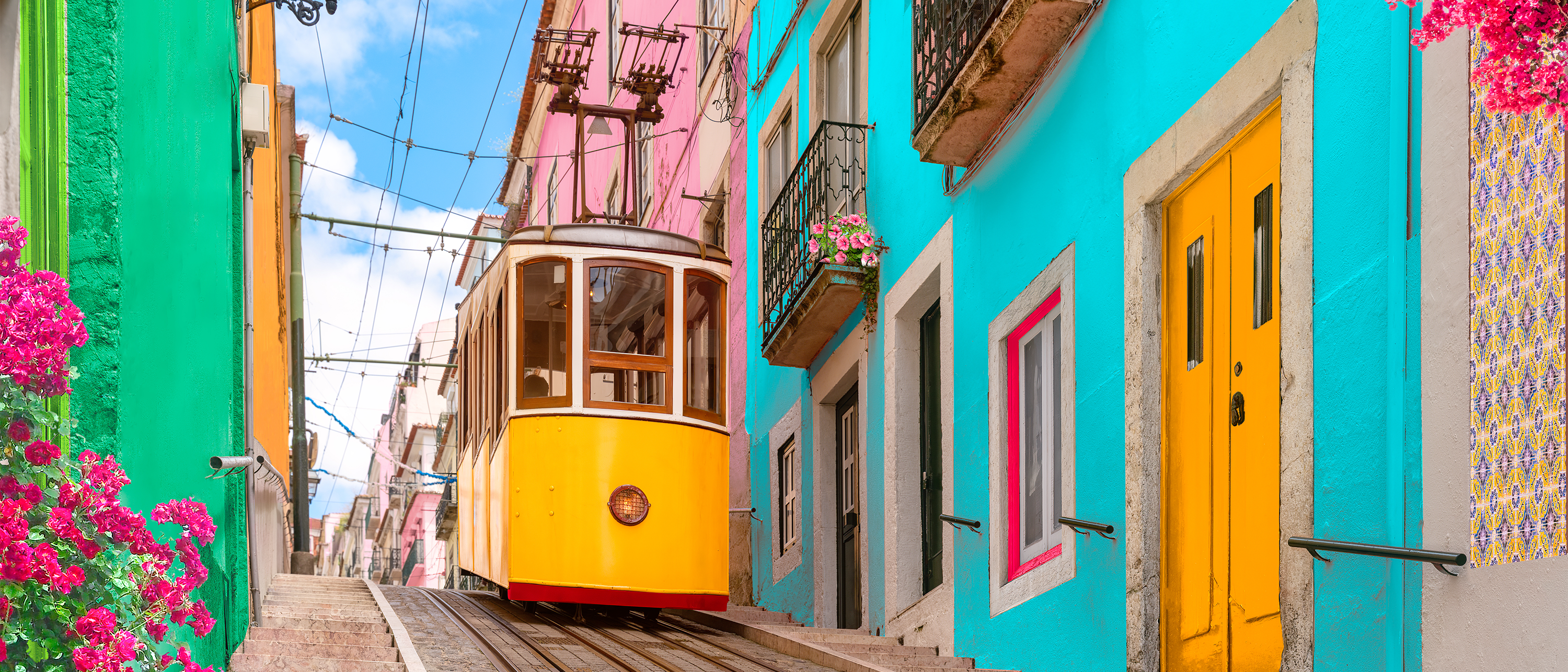 A yellow tram descends a narrow street lined with colorful buildings in Lisbon, Portugal.