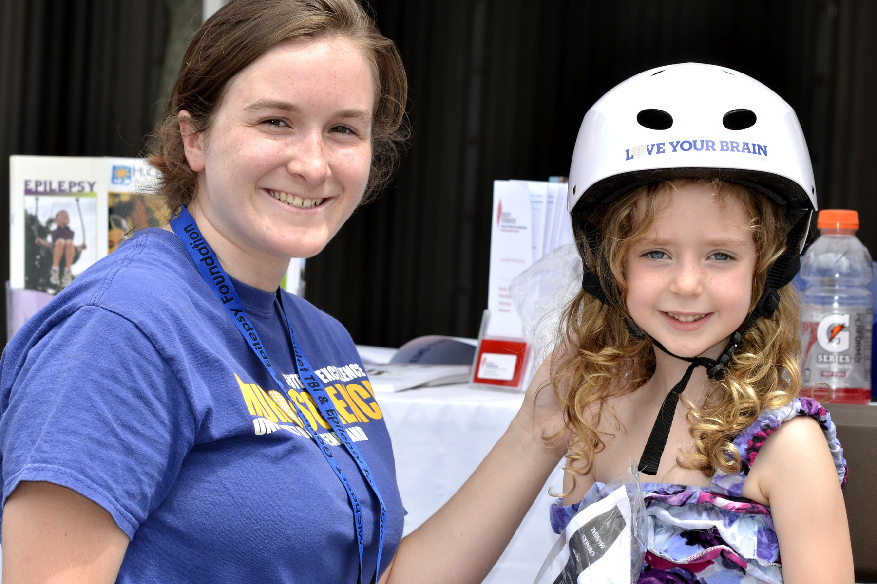 A female U N E student stands with a young girl wearing a bike helmet 