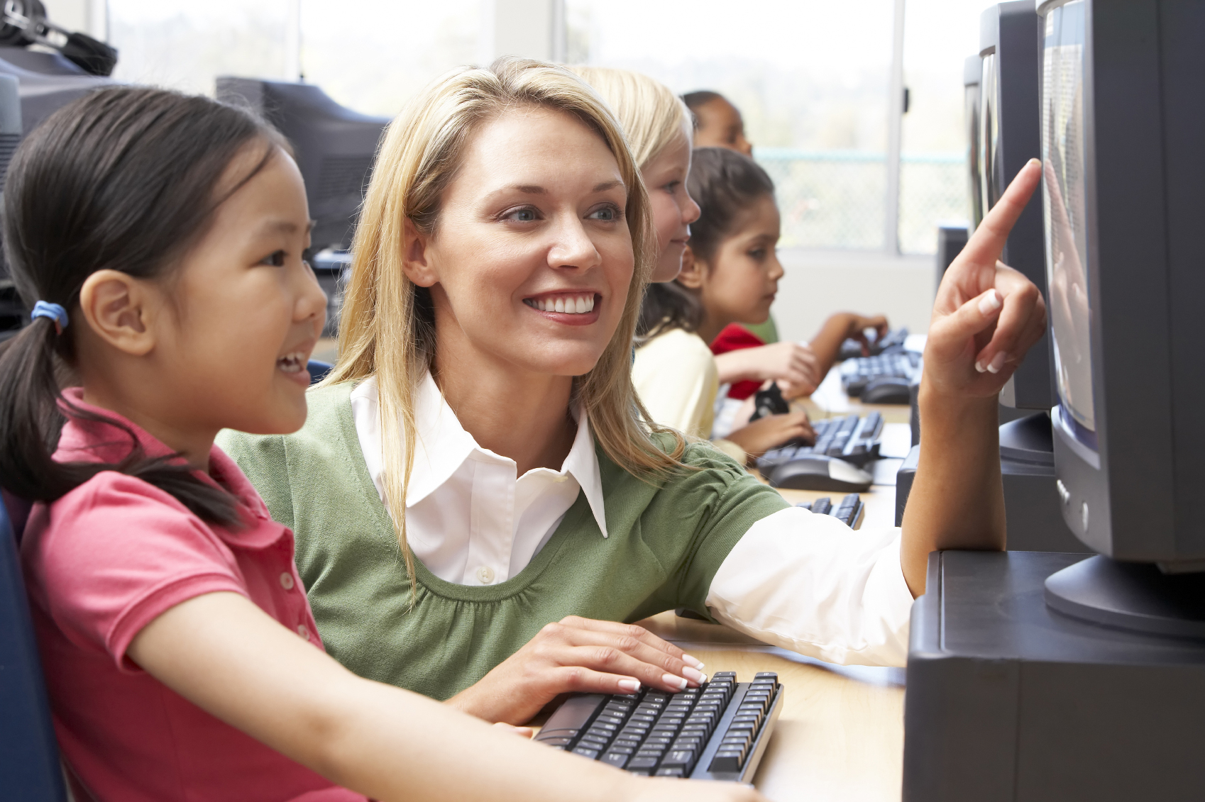 A female education major instructs a young girl working on a computer 