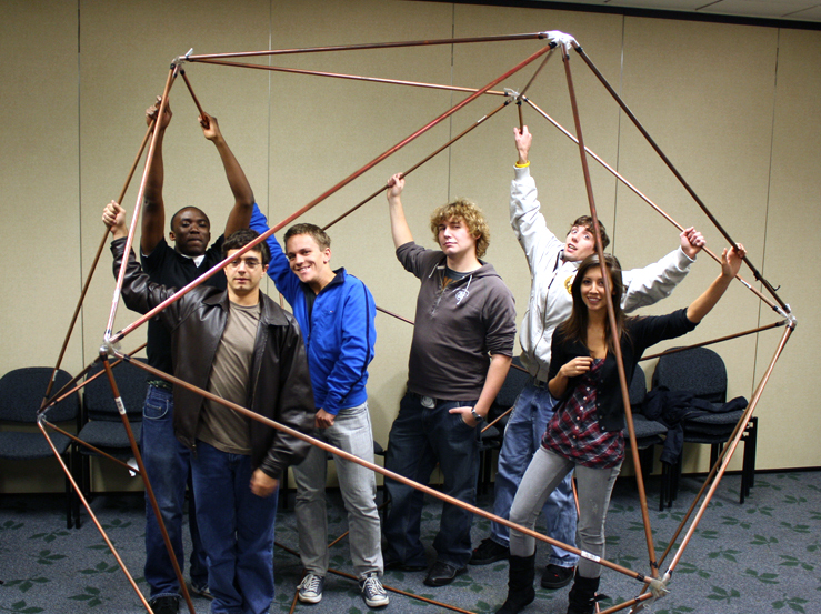 Members of the U N E Math Club stand inside a giant metal model they've built