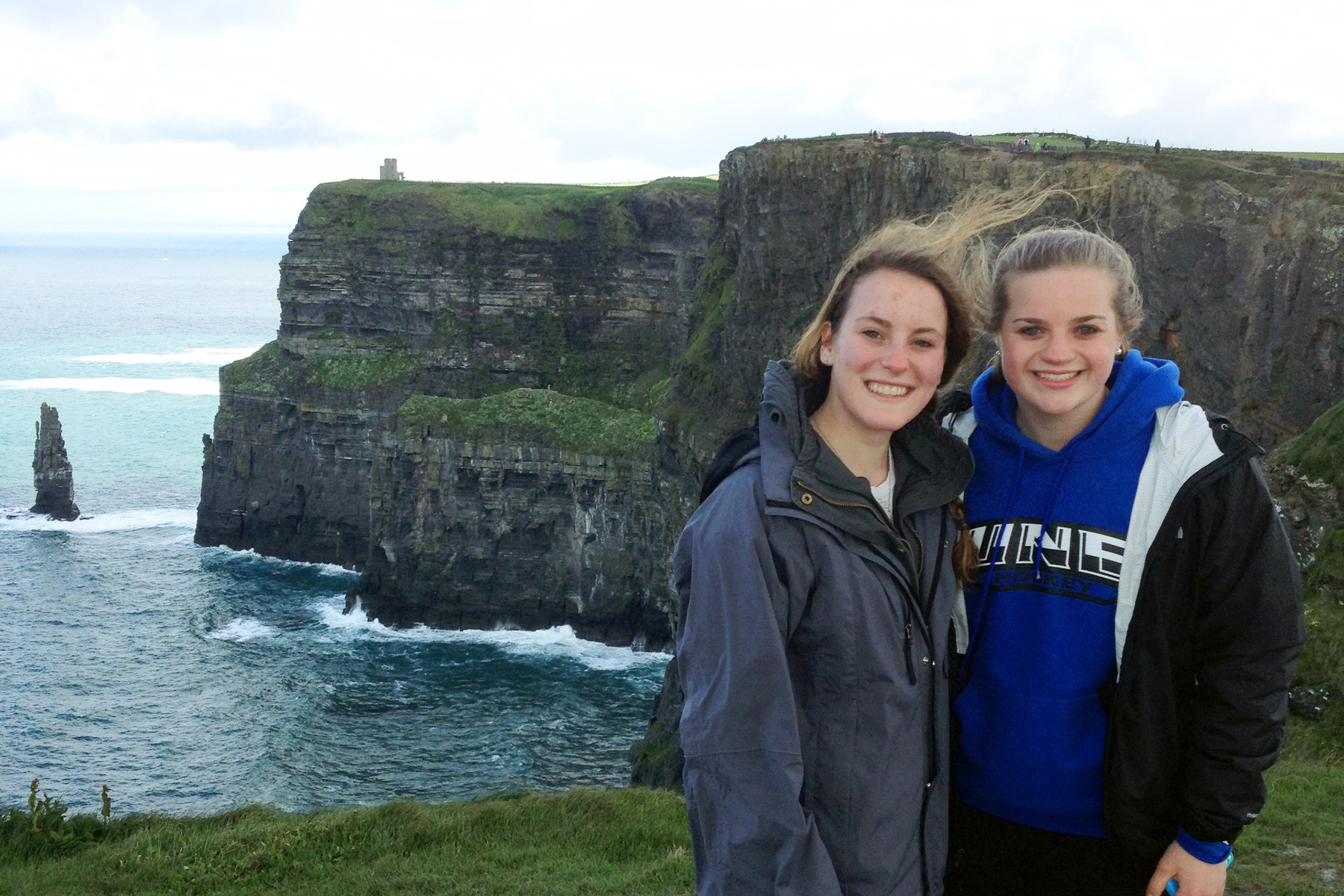 Two female students pose on a seaside cliff in Ireland 