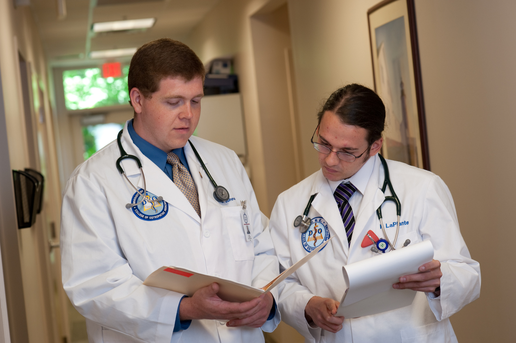 Two U N E medical students stand in a hallway examining a patient's chart