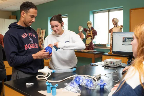 Two students prepare a medical tool for testing lung capacity