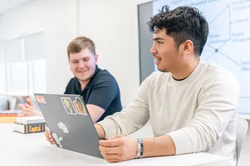 Students talk while studying at their laptops