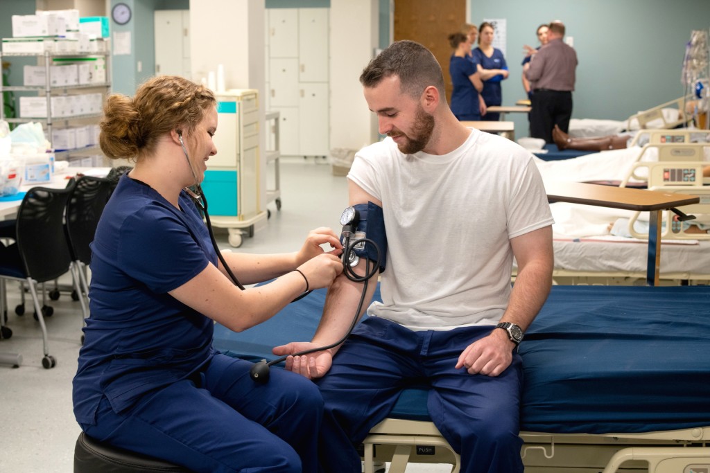 A nursing student takes another student's blood pressure in UNE's Interprofessional Simulation and Innovation Center