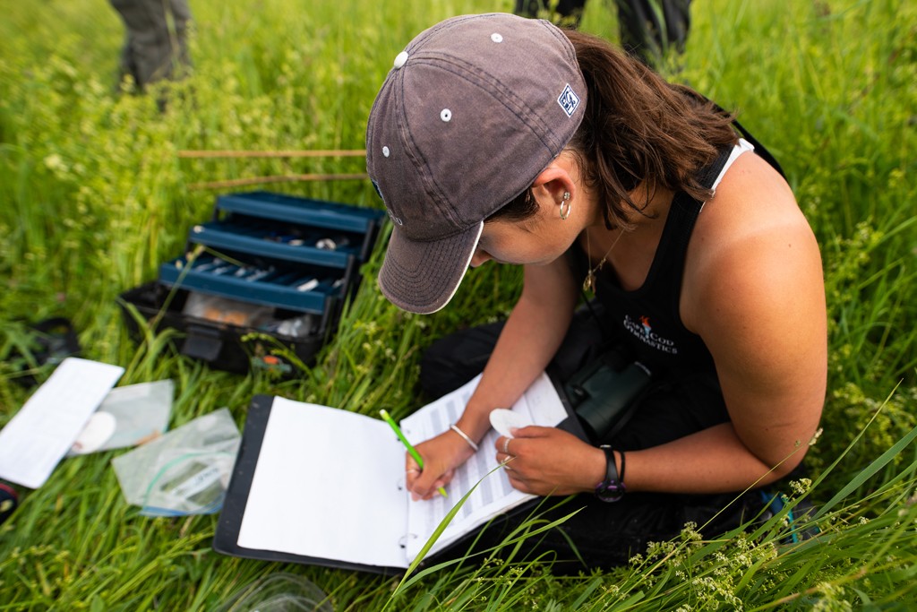 A U N E student takes notes while doing environmental field work