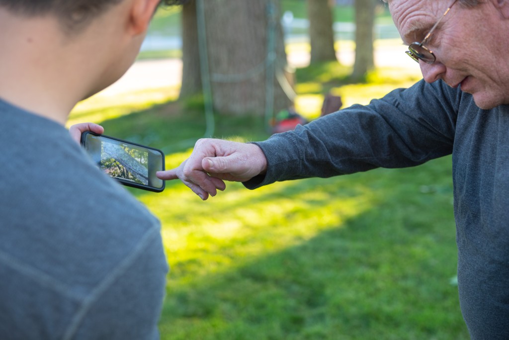 Students look at a cell phone with the image of a tree