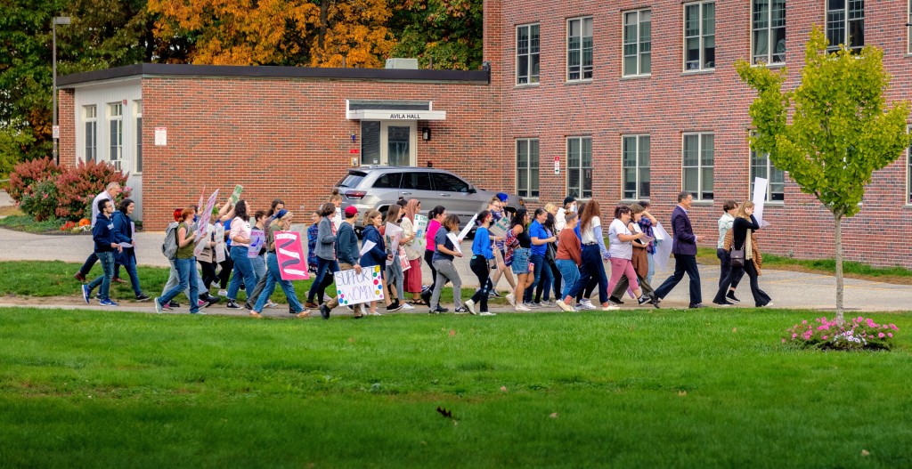 A group of students march by a dorm