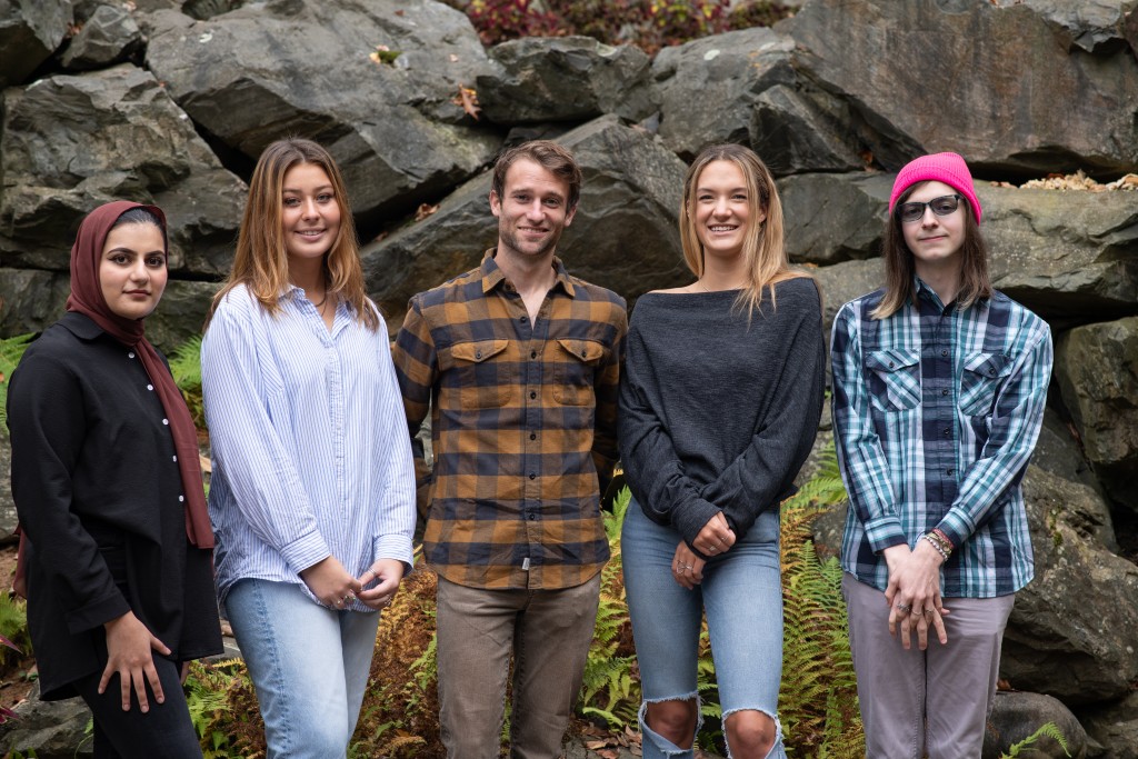 Five UNE students pose against a rocky background