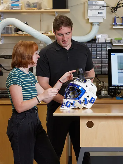 Two students examine a device for improving goaltending
