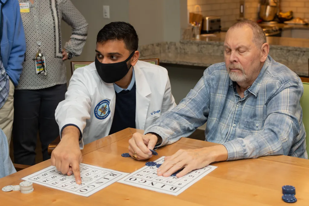 Vrushabh Daga plays bingo with a man at The Cedars in Portland